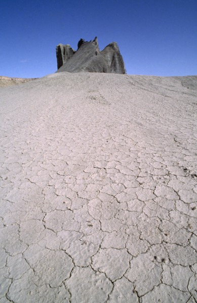 USA, Utah, North Pinto Hills, View over cracked dry earth toward rock formation on the horizon