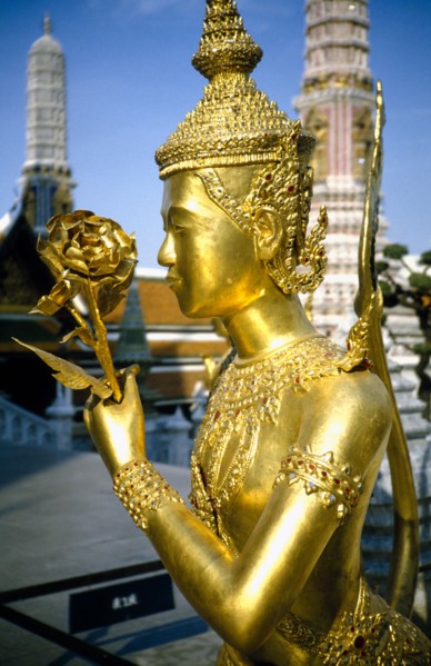 THAILAND, Bangkok, Wat Phra Kaew, Or Royal Palace. Golden temple statue of a figure holding a