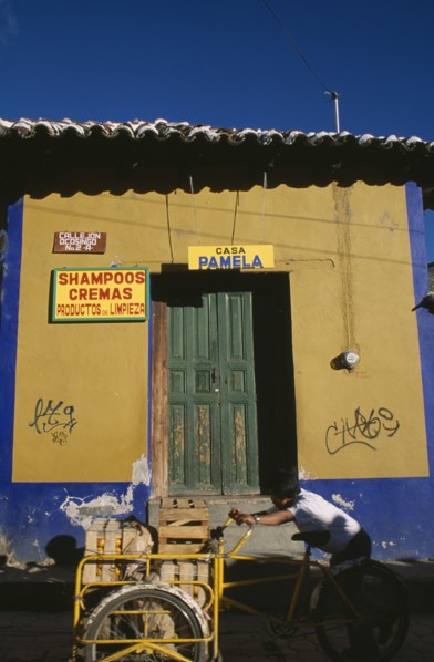 MEXICO, Chiapas, San Cristobal de Las Casas, Man pushing bicycle handcart stacked with crates of
