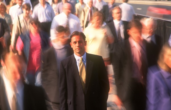 BUSINESS, Commuters, City businessman in suit standing motionless surrounded by crowds in blurred