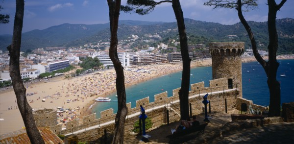 SPAIN, Catalonia, Tossa de Mar, View over busy sandy beach and town from fortified walls of Villa