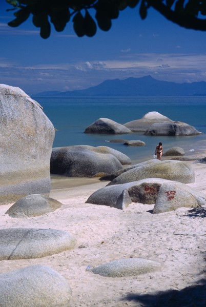 MALAYSIA, Penang, Batu Ferringhi, "Sandy beach with woman in bikini walking out of sea between