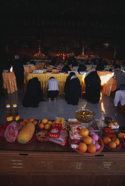 MALAYSIA, Penang, Kek Lok Si Temple, Morning prayers in the main prayer hall. Kneeling worshippers