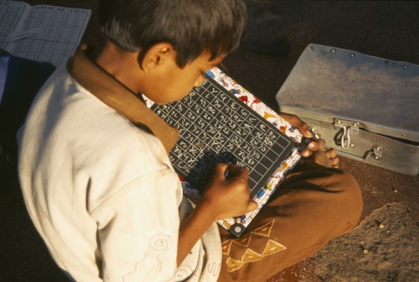 INDIA, Maharashtra, Nasik, School boy using chalk and slate