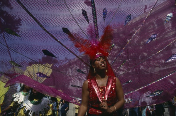 ENGLAND, London, "Notting Hill Carnival, dancer in pink and red costume following a float."