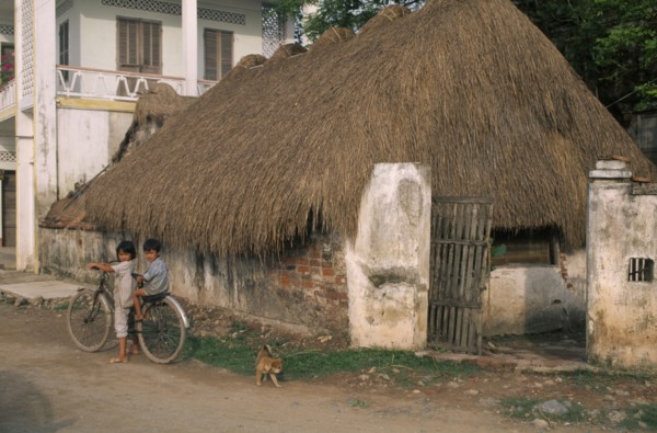 VIETNAM, Phat Diem , Village housing and children on bicycle.
