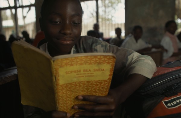 TANZANIA, Shinyanga, Mwenge Primary School child reading a text book in the classroom