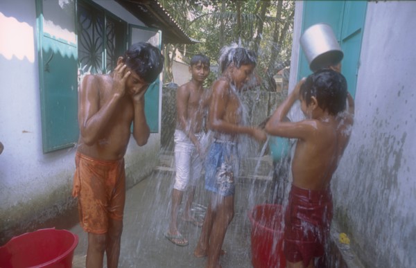 BANGLADESH, Savar, Dhaka, Street boys in a refuge home bathing using buckets and cups.