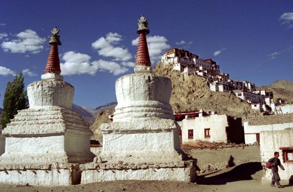 INDIA, Ladakh, Tikse, Tikse Gompa. Twin red and white stupas with hilltop architecture beyond