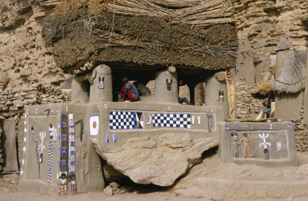 MALI, Bandiagara Cliffs, Newly painted Dogon Toguna or meeting place with men sitting on raised