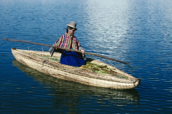 PERU, Puno, Lake Titicaca, Uros woman on reed boat rowing to floating island.