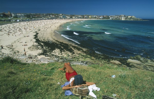AUSTRALIA, New South Wales, Sydney, View over Bondi beach with woman sunbathing in the foreground