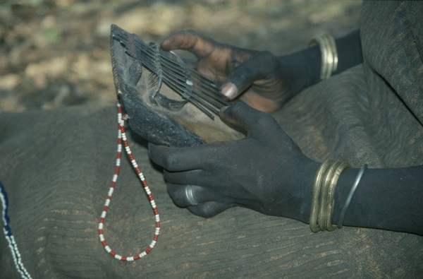 ETHIOPIA, Music, Cropped view of Mursi girl playing traditional thumb piano musical instrument.