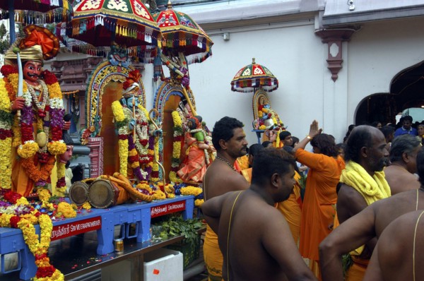 SINGAPORE, , Men and women standing beside a colourful shrine decorated with flower garlands at an