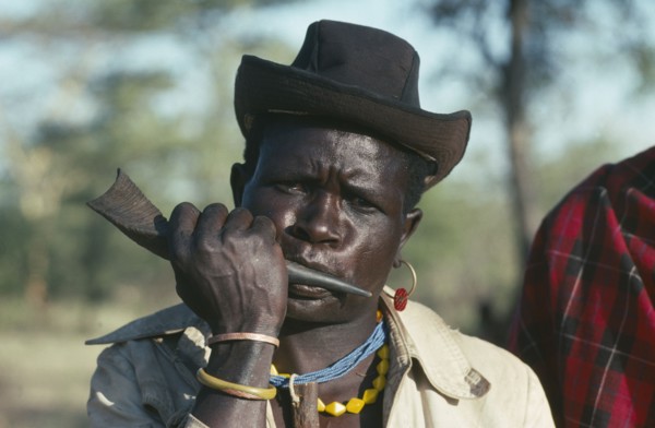 UGANDA, Karamoja  , Portrait of a Dodoth Karamojong warrior blowing an antelope horn to call a