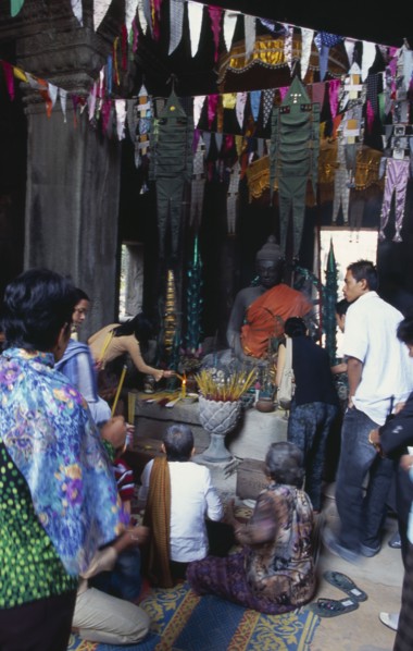 CAMBODIA, Siem Reap Province, Angkor, Banteay Kdei.  Cambodian visitors lighting incense at shrine