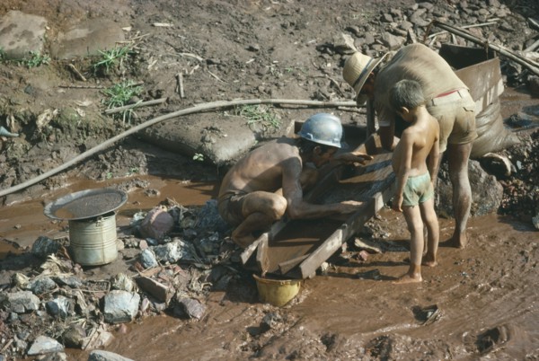 BRAZIL, Serra Pelada, Men panning for gold watched by child.