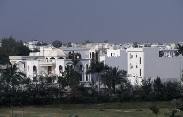 OMAN, Muscat, White painted housing amongst palms.