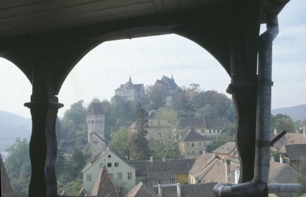 ROMANIA, Transylvania, Mures, Sighisoara.  View of town rooftops framed by archway.  Famous as