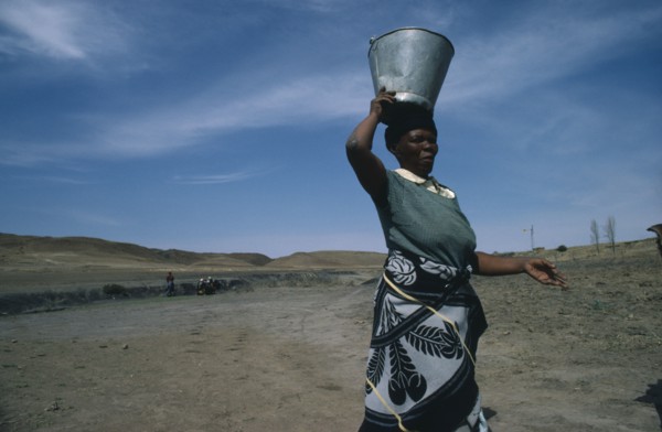 LESOTHO, Water, Woman carrying water from well on her head.