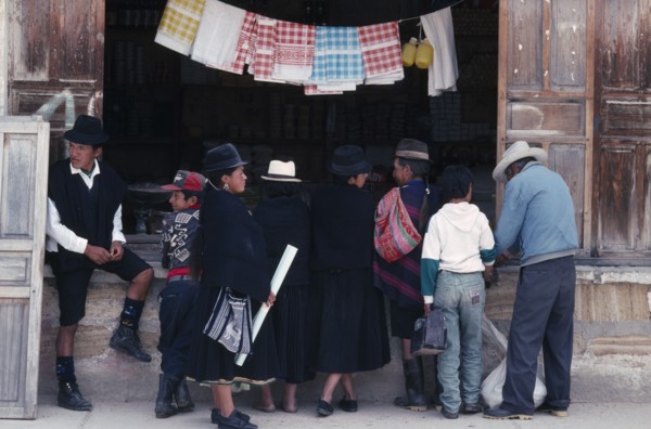 ECUADOR, Loja, Saraguro, Customers in mix of traditional and westernised dress outside shopfront.