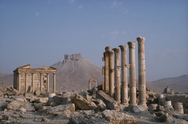SYRIA, Palmyra, Roman ruins with columns and pillars and The Islamic Fort in the distance.