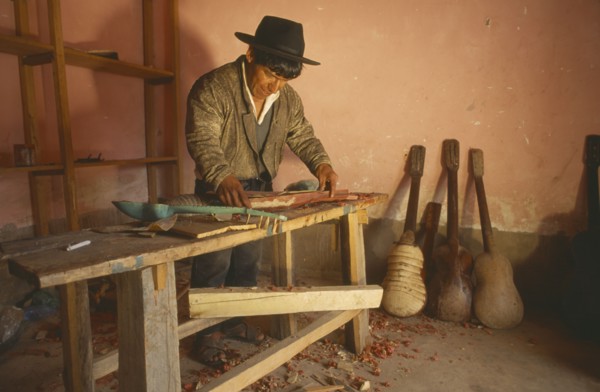 BOLIVIA, Chuquisaca, Tarabuco, Charango musical instrument maker at workbench.