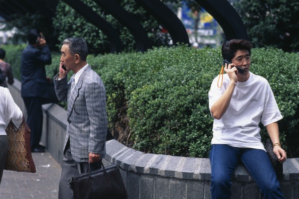 JAPAN, Shibuya, Tokyo, Three men ranging in age talking on mobile phones.