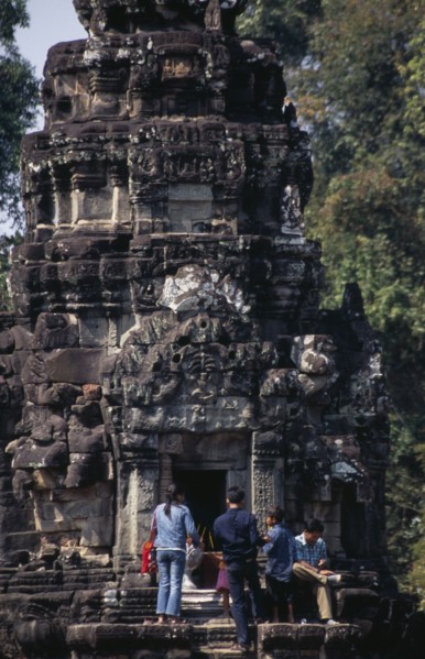 CAMBODIA, Siem Reap Province, Angkor, Neak Pean.  Tourists lighting incense at entrance to small