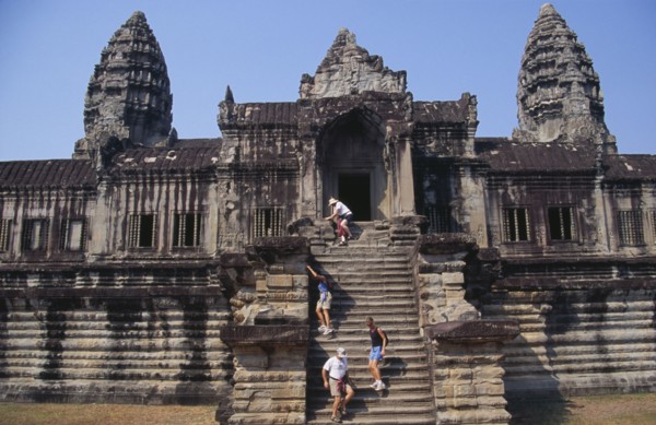 CAMBODIA, Siem Reap Province, Angkor Wat, Western tourists climbing steep and narrow set of steps