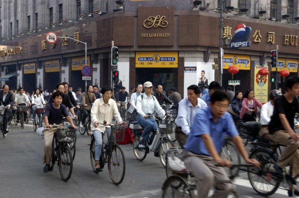 CHINA, Shanghai, Mass of cyclists passing a crossroads at the traffic lights outside the Hui Luo Co