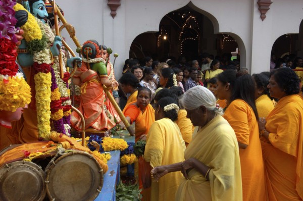 SINGAPORE, , Women standing beside a colourful shrine decorated with flower garlands at an Indian