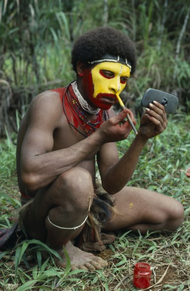 PAPUA NEW GUINEA, Southern Highlands, Tari Valley, Huli tribesman painting his face using old car
