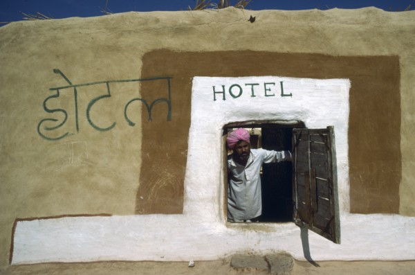 INDIA, Rajasthan, People, Man in turban looking out of low open doorway of village hotel.