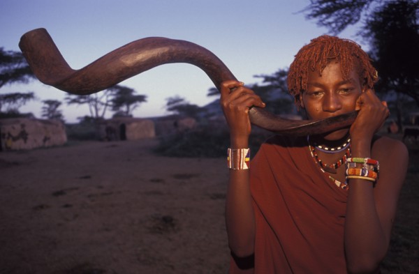 KENYA, Kajiado, A Maasai Moran blows an Ikudu horn as part of innitiation ceremony bringing the
