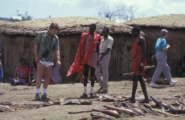 KENYA, , An American tourist haggles with a Maasai man in a cultural manyatta set up to interface
