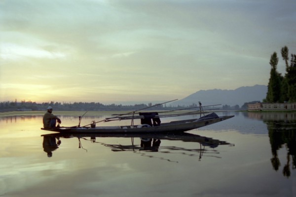 INDIA, Kashmir, Srinagar, Nagin Lake. Fisherman sitting at the very end of his canoe in the evening