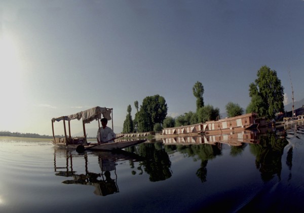 INDIA, Kashmir, Srinagar, Nagin Lake. Man in Shikara or Water Taxi with two modern houseboats