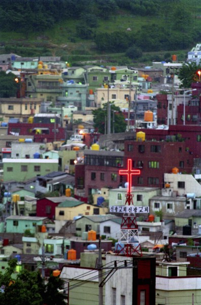 SOUTH KOREA, Pusan, View over housing in city suburb with illumintaed church cross