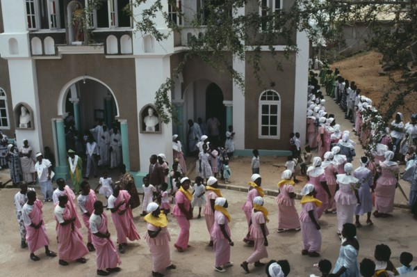 GHANA, Religion, Easter, Men and women in traditional pink dress leaving the Easter Sunday service
