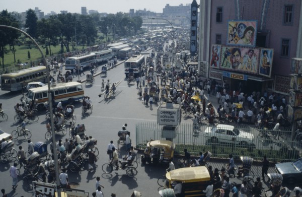 BANGLADESH, Dhaka, Busy street scene with crowds of pedestrians trishaws and buses.  Cinema with