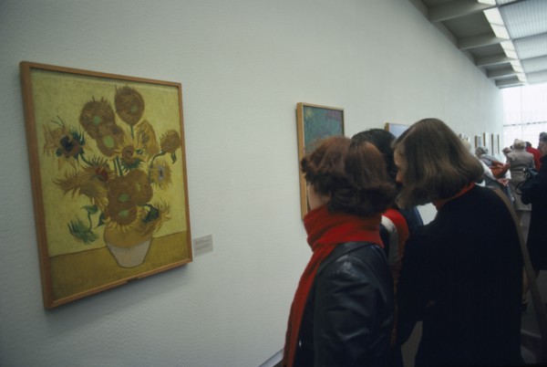 HOLLAND, North, Amsterdam, Visitors inside the Van Gogh Museum looking at painting of Sunflowers.