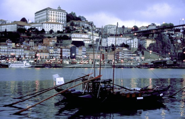 PORTUGAL, Porto, Oporto, View over boats moored in the port toward the city illuminated at dusk