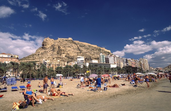 SPAIN, Alicante, Busy beach scene with clifftop castle beyond