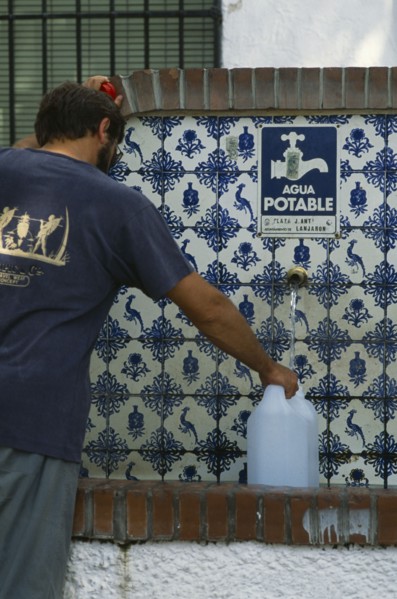 SPAIN, Andalucia, Granada, Lanjaron. Man collecting water from a drinking fountain in this Sierra