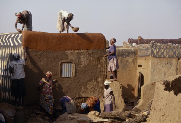 BURKINA FASO, Tiebele, Group of women preparing house front for decorative painting in traditional
