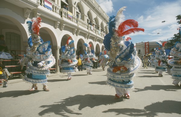 BOLIVIA, Oruro, Carnival masqueraders in colourful animal costumes in a street lined with colonial