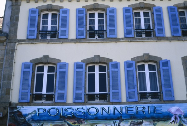 FRANCE, Brittany, Finistere, Douarnenez. Blue shuttered windows over Poissonnerie sign.
