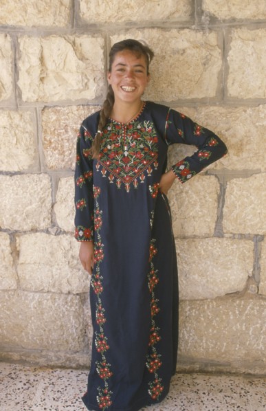 WEST BANK, People, Young woman in traditional Palestinian embroidered dress in National colours
