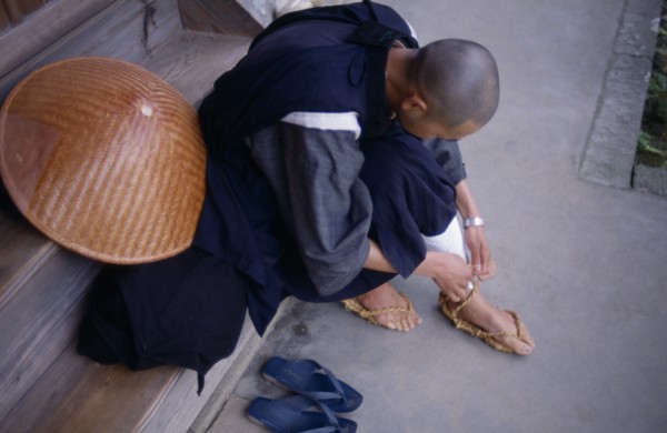 JAPAN, People, Bukokuji Monastery with Zen Buddhist monk tying up thong sandal made of rope.